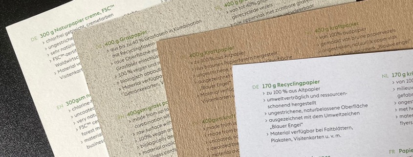 Foto von vier Bögen Papiermuster umweltfreundlicher Materialien (Cremepapier, Graspapier, Kraftpapier und Recyclingpapier).